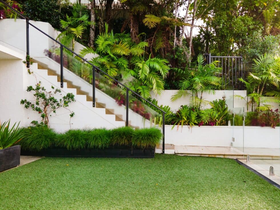 Landscaped residential yard with artificial turf and garden beds